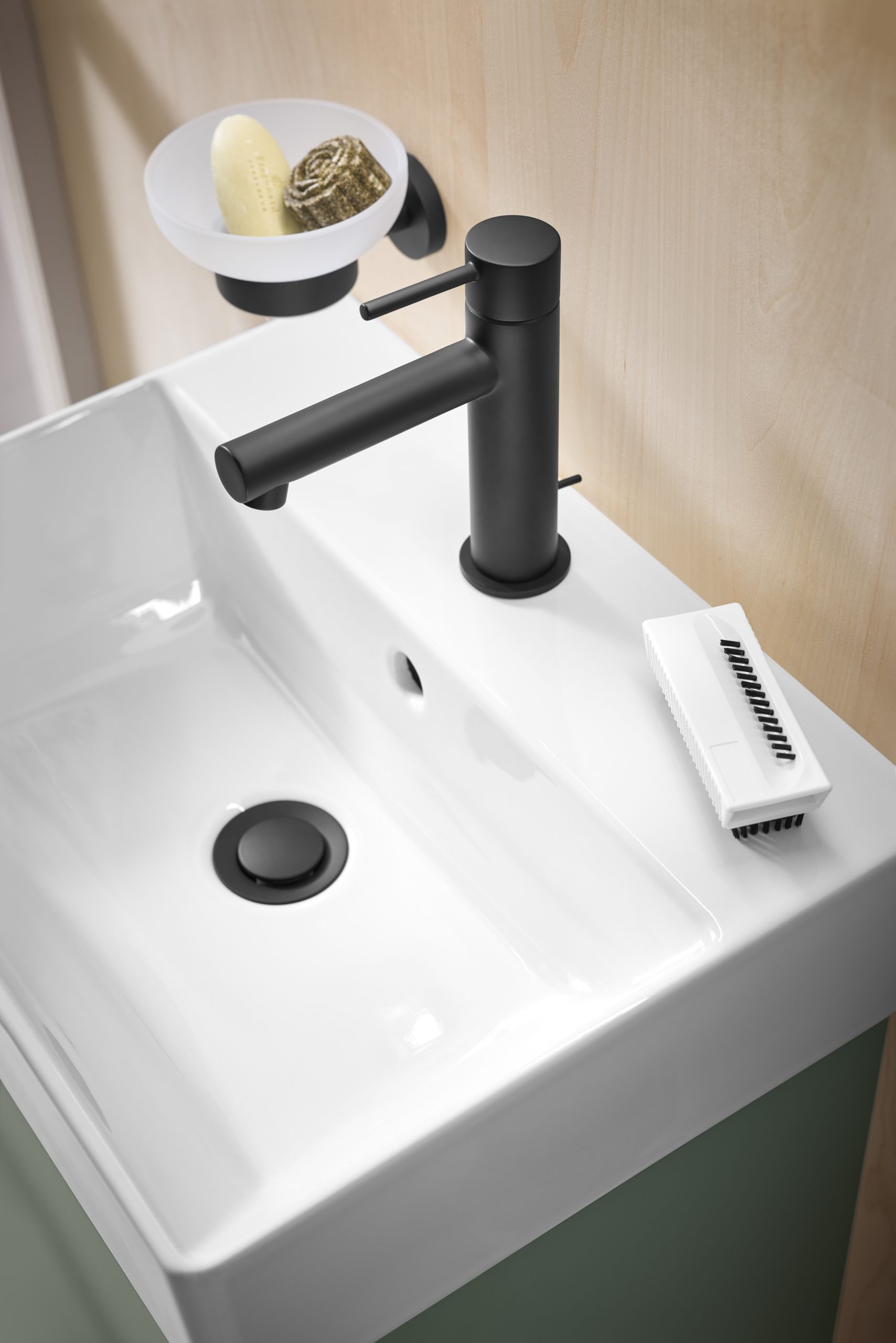 Weißes Waschbecken mit schwarzem Einhebelmischer und Seifenspender in hellem Bad.