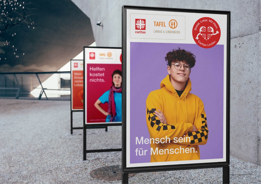 Mann in Warnweste vor Plakat „Mensch sein für Menschen“ mit Caritas- und Tafel-Logos