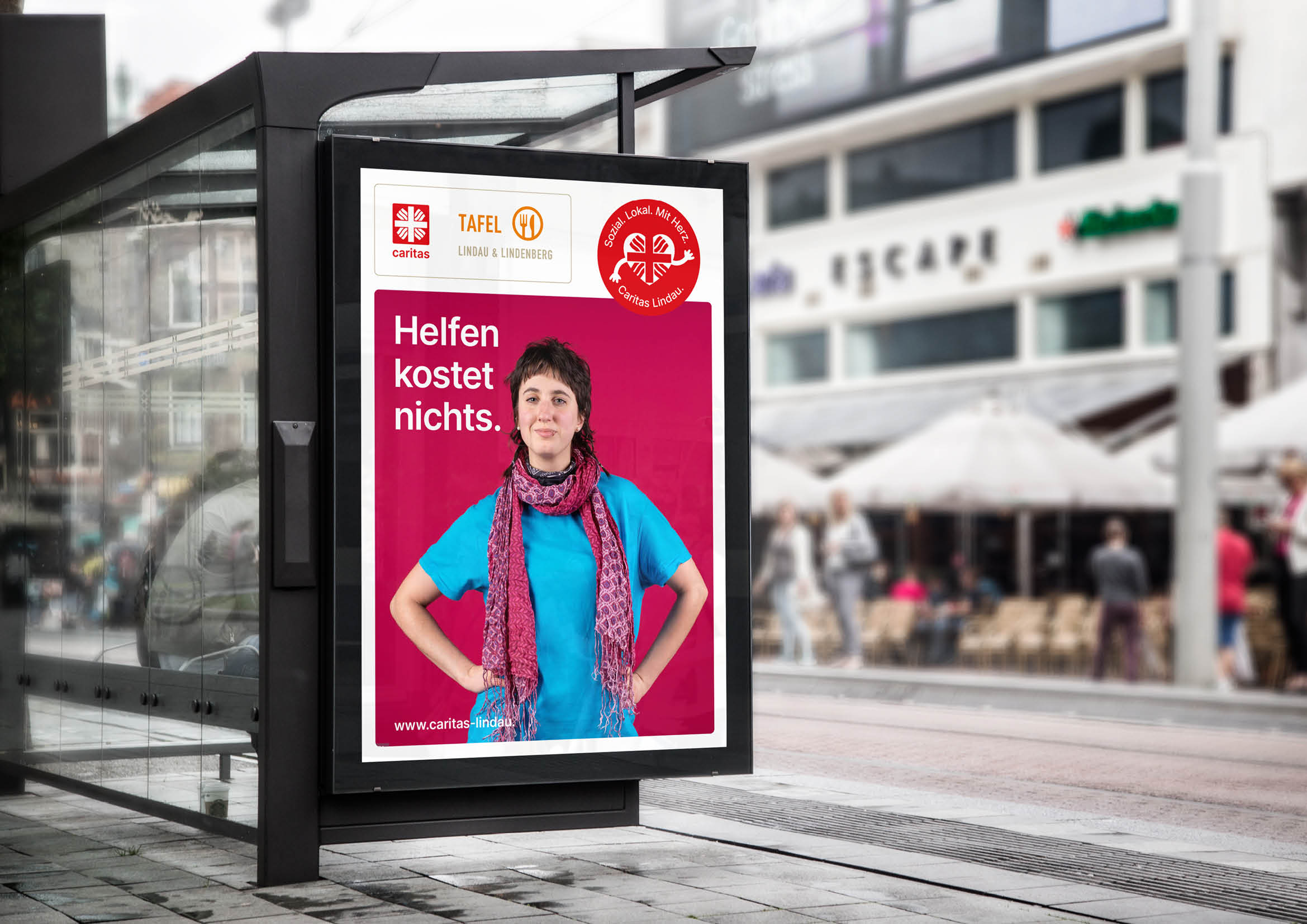 Frau lacht vor Plakat „Helfen kostet nichts.“ mit Logo Caritas und Tafel