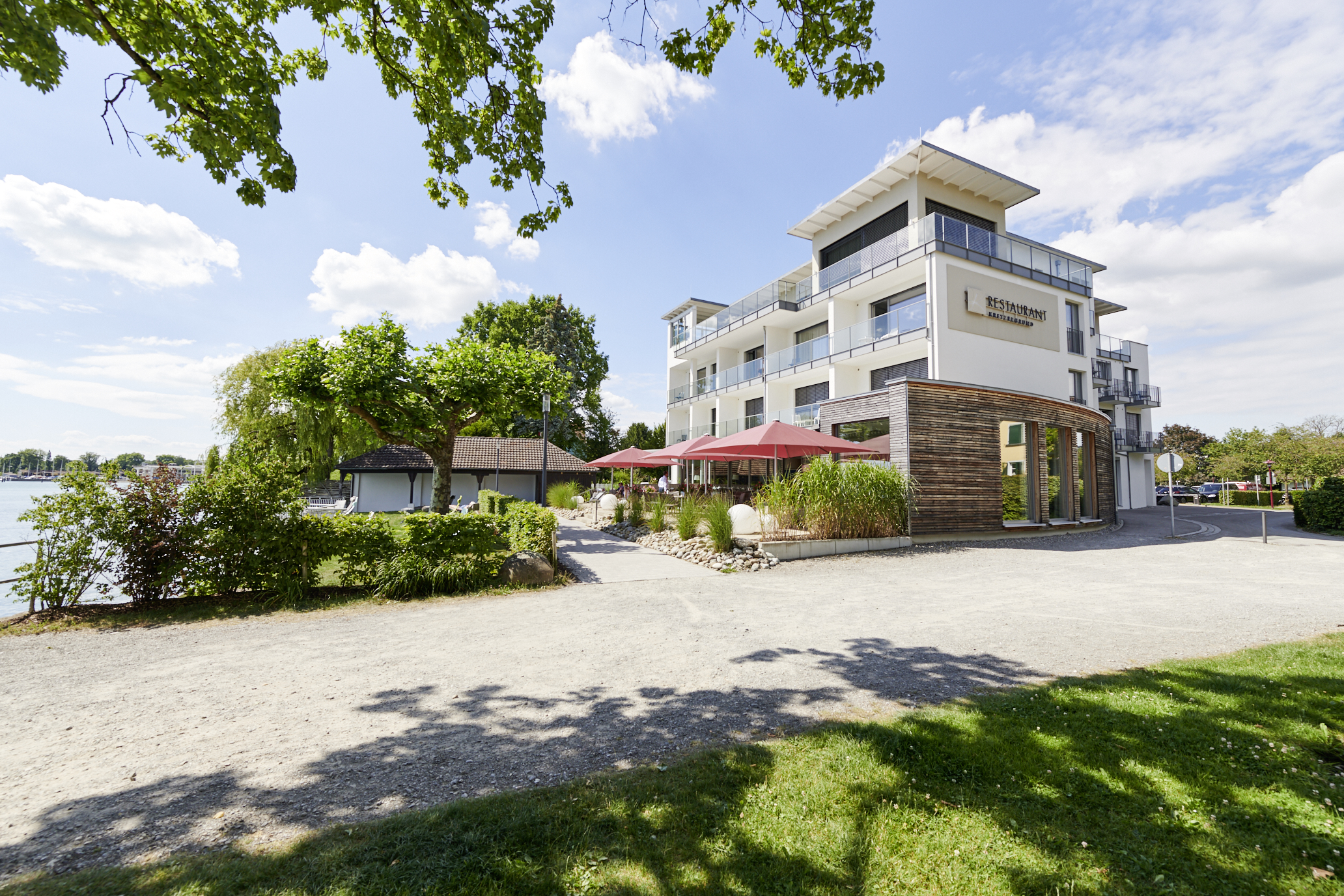 Weißes Hotelgebäude mit Restaurant-Schild und Parkplatz