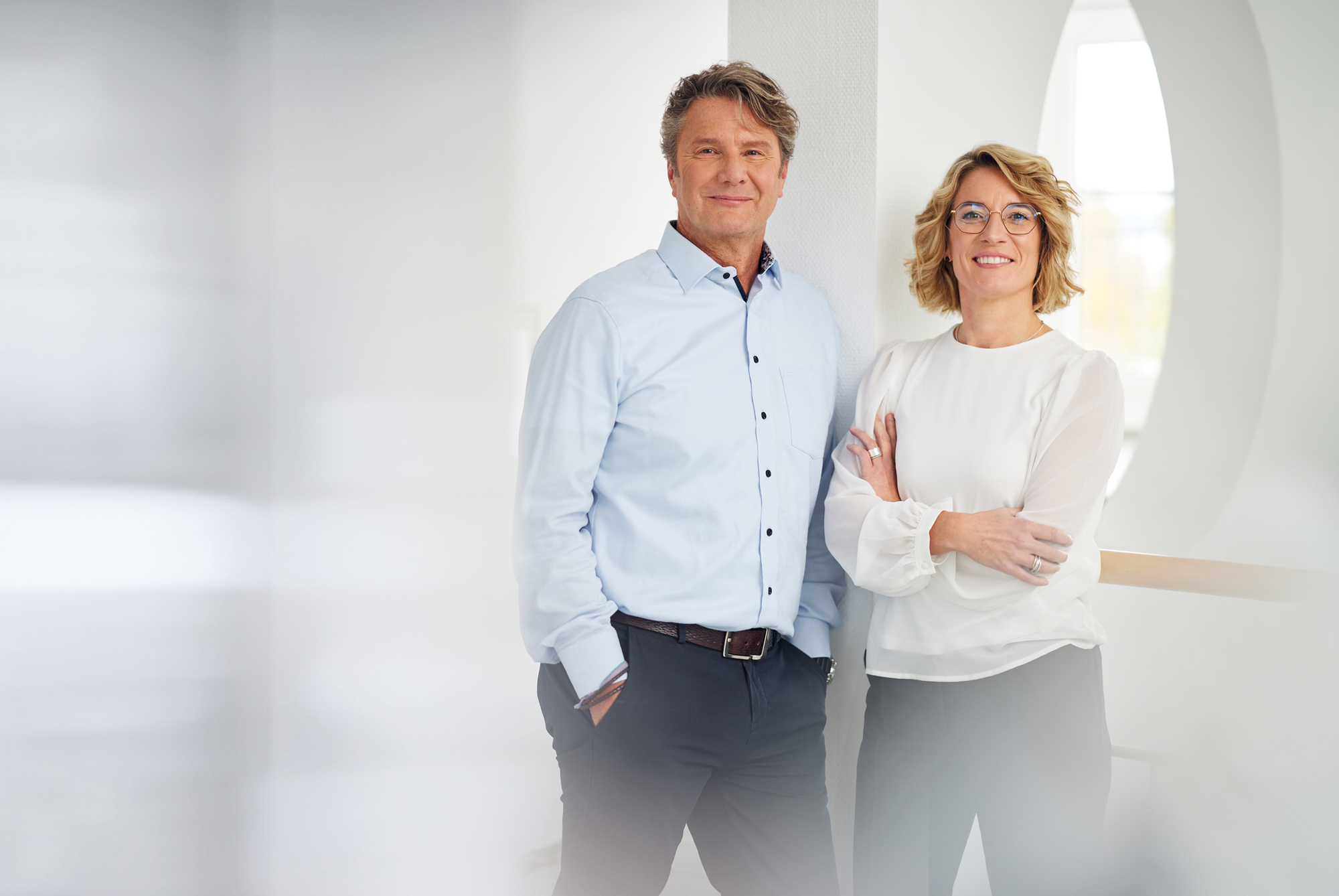 Zwei Personen in Business-Kleidung lächeln in die Kamera