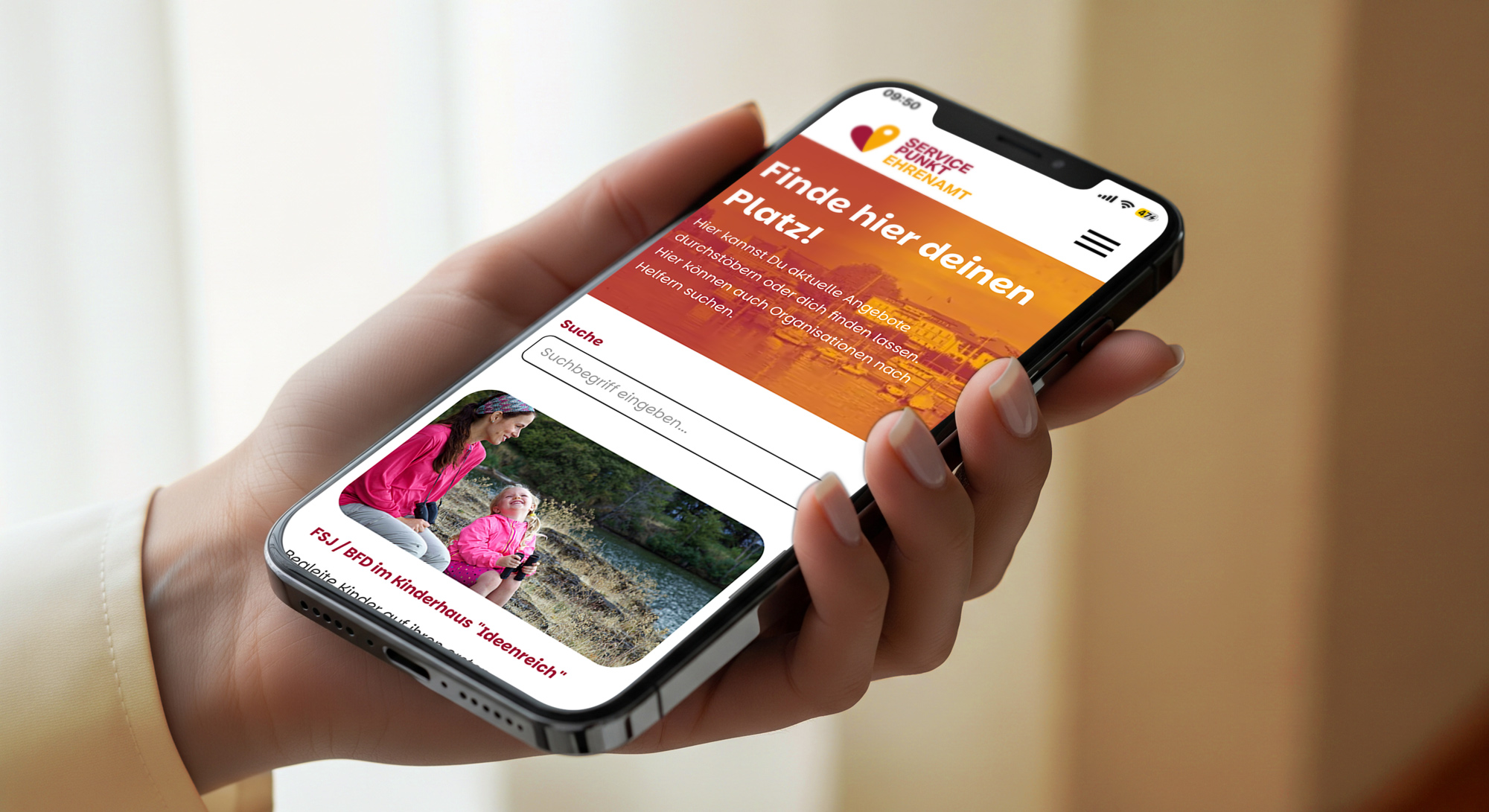 Hand hält Smartphone mit App „Finde hier deinen Platz!“ und Suchfeld